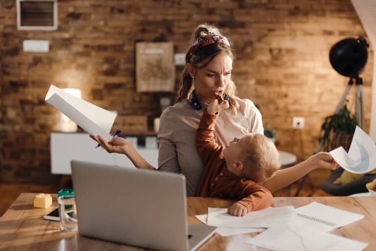 working mother feeling stressed out while son is distracting her feeding her with cookie